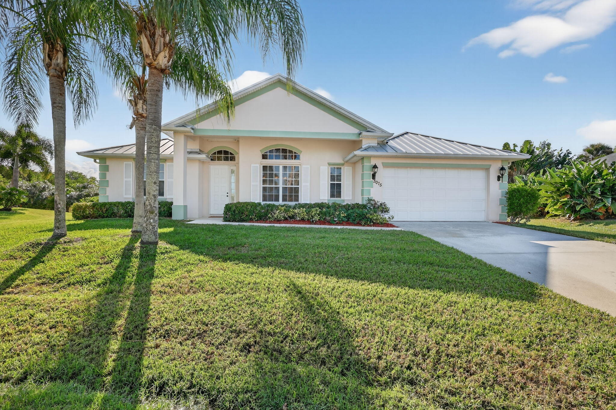 3075 73rd Place Vero Beach, FL 32967 - Photo 2 of 65 a front view of a house with a garden and palm trees
