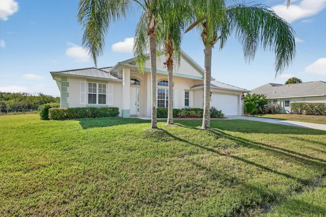 a view of a house with a yard and palm trees