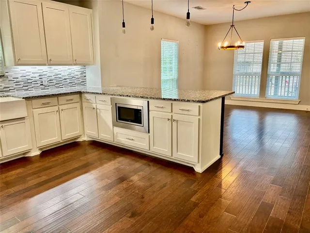 a kitchen with stainless steel appliances granite countertop a sink a stove a microwave and wooden floor