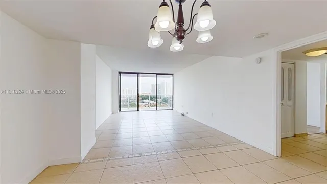 a view of an empty room with a chandelier fan