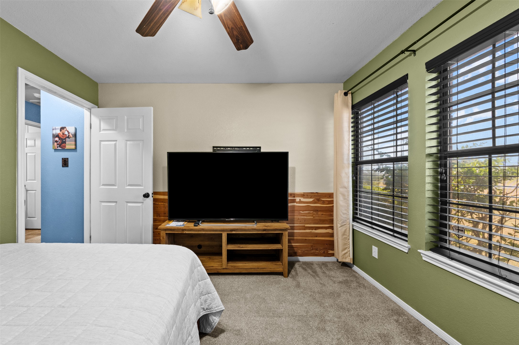 1512 Panther Loop Pflugerville, TX 78660 - Photo 13 of 40 Well-lit sleeping quarters with a ceiling fan, plush carpeting, and horizontal wooden accent paneling.