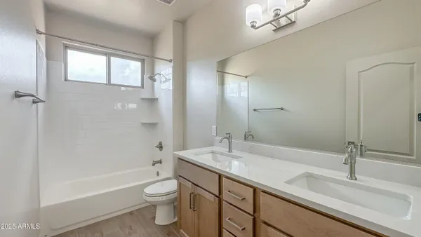 a bathroom with a double vanity sink toilet mirror and bathtub
