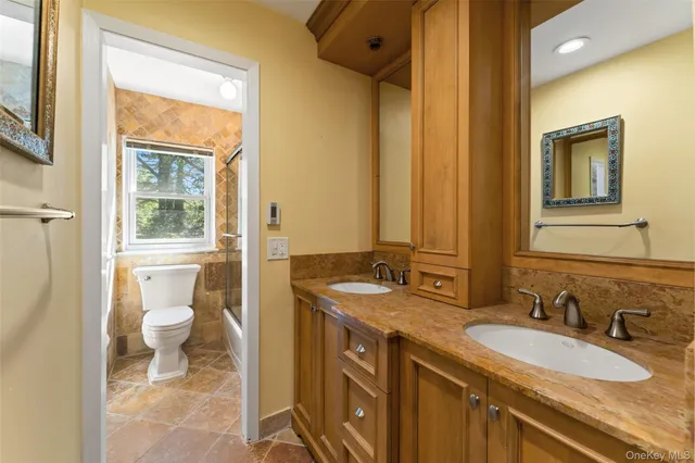 a bathroom with a granite countertop sink toilet and mirror