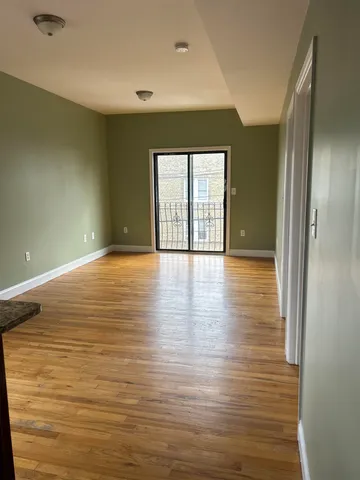 a view of an empty room with window and wooden floor