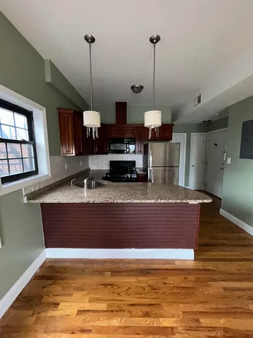 a view of a kitchen with stainless steel appliances granite countertop a sink a stove and a wooden floors