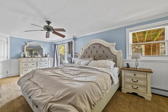 a bedroom with a bed a dresser and a chandelier