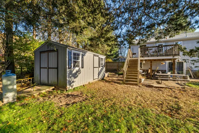 a backyard of a house with large trees and wooden fence