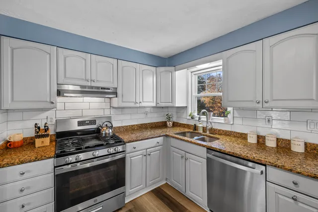 a kitchen with granite countertop a sink stainless steel appliances and cabinets