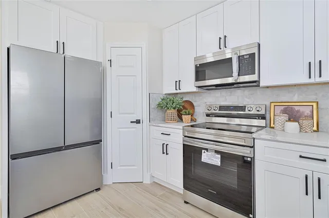 a kitchen with stainless steel appliances white cabinets and a refrigerator