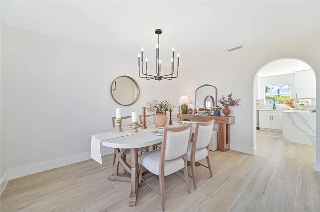 a dining room with wooden floor a chandelier a wooden table and chairs