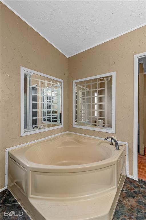 9720 Osburn Road Shreveport, LA 71129 - Photo 15 of 30 Corner soaking tub with deck-mounted faucet, complemented by two decorative wall mirrors and textured wall finish