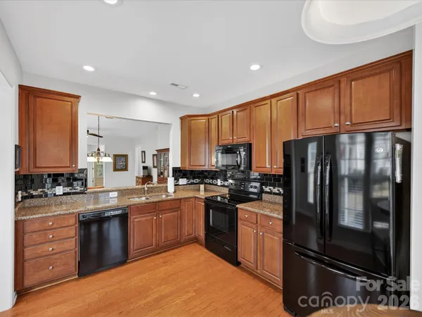 a kitchen with stainless steel appliances granite countertop a stove a sink dishwasher a refrigerator and cabinets with wooden floor