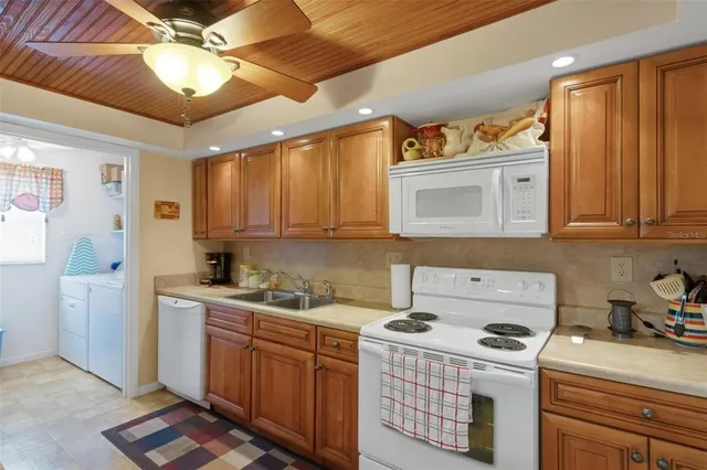 a room with a sink wooden cabinets and washer dryer