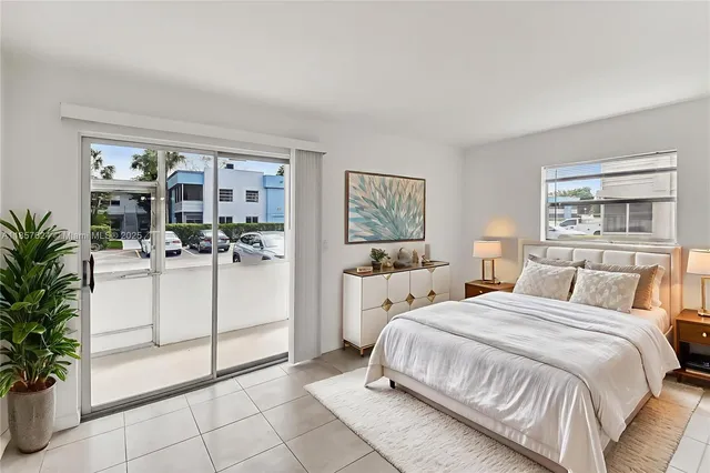 a large white bed sitting in a bedroom next to a window with potted plants