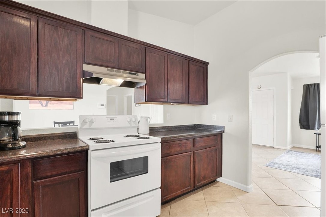 4391 Emma Street Pahrump, NV 89048 - Photo 13 of 28 Kitchen featuring white range with electric stovetop, dark countertops, arched walkways, and under cabinet range hood