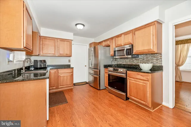 a kitchen with stainless steel appliances granite countertop a refrigerator a stove top oven a sink and dishwasher