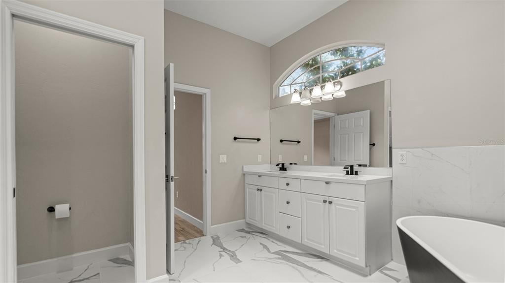 9428 Southwest 39 Avenue Gainesville, FL 32608 - Photo 34 of 43 a spacious bathroom with a granite countertop sink a toilet and a mirror