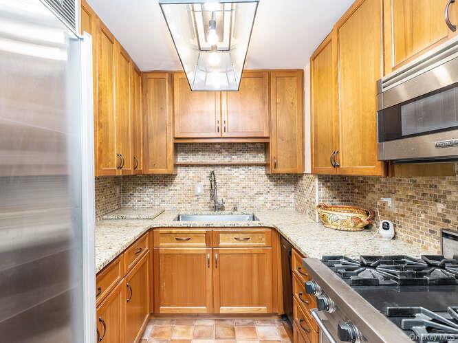 225 East 57th Street, Unit 1L Manhattan, NY 10022 - Photo 11 of 20 a kitchen with stainless steel appliances granite countertop a stove a sink and a microwave