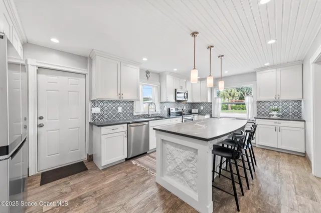 a large kitchen with granite countertop a large counter top a sink stainless steel appliances and cabinets