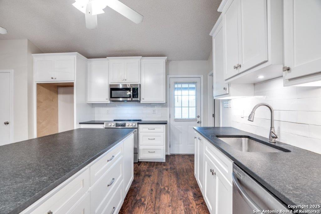 218 Ebner Street Boerne, TX 78006 - Photo 12 of 24 a kitchen with granite countertop a sink stainless steel appliances and white cabinets