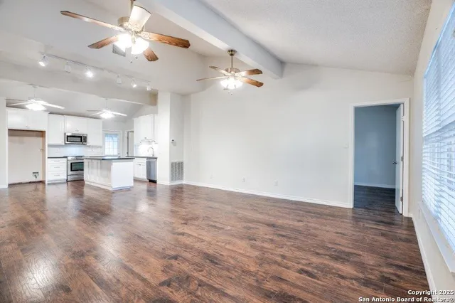 an empty room with wooden floor cabinet and windows