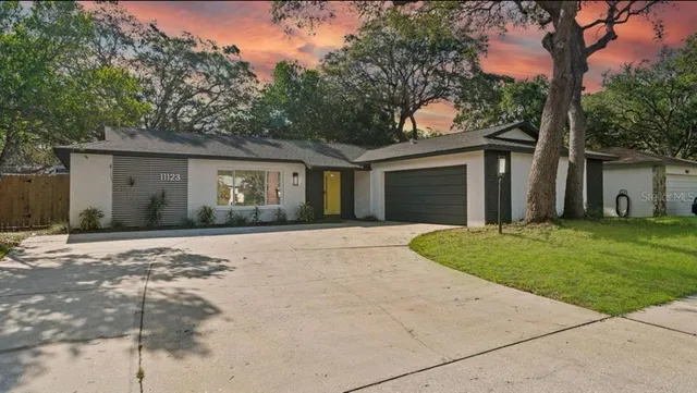 a front view of a house with a garden and trees