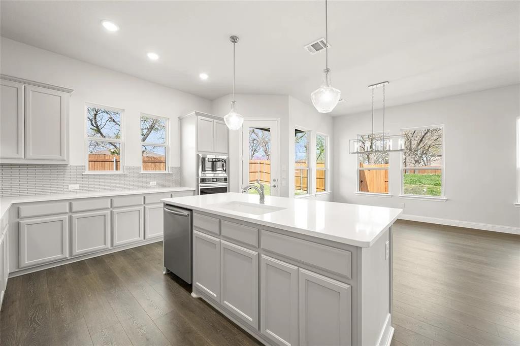 4021 Alpine Street Midlothian, TX 76065 - Photo 5 of 18 Open-concept kitchen featuring light-colored cabinetry, stainless steel appliances, a center island with sink, and wood-finish flooring