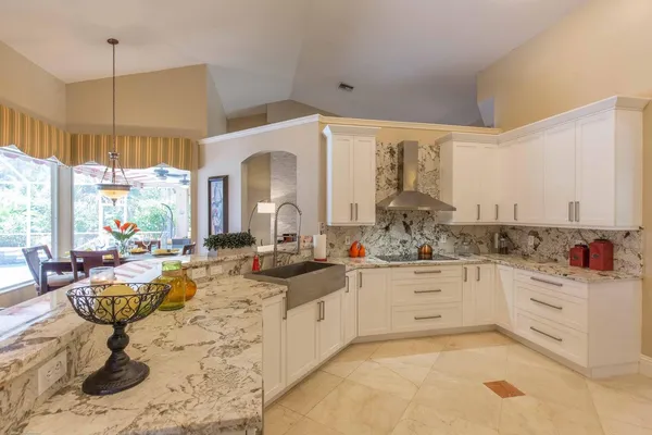 a very nice looking open kitchen with granite countertop a sink white cabinets and a wooden floor