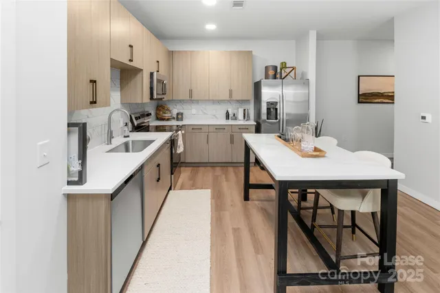 a kitchen with stainless steel appliances granite countertop a sink a stove a refrigerator cabinets and chairs