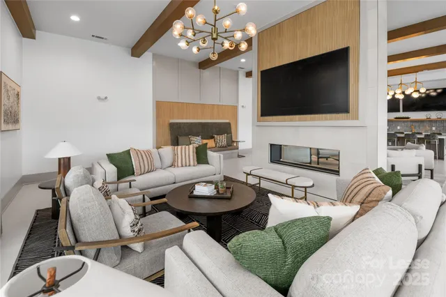a living room with furniture a flat screen tv and kitchen view