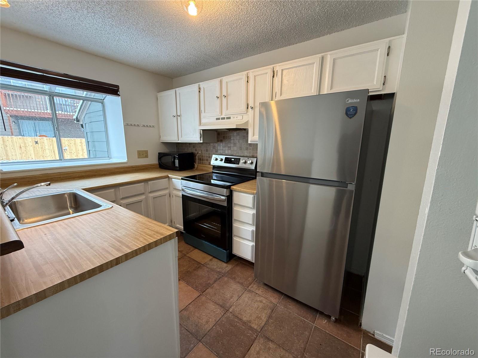 17315 East Rice Circle, Unit G Aurora, CO 80015 - Photo 13 of 31 a kitchen with a refrigerator a stove top oven a sink and dishwasher
