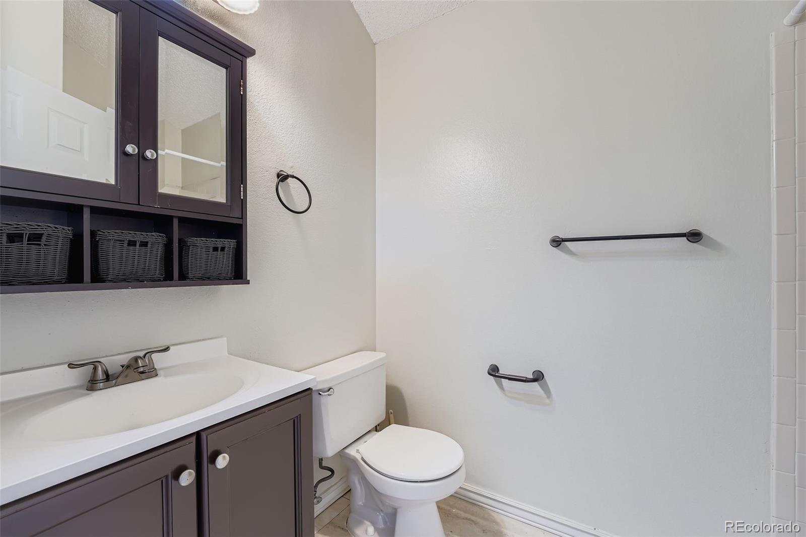 17315 East Rice Circle, Unit G Aurora, CO 80015 - Photo 20 of 31 a bathroom with a toilet a sink and mirror