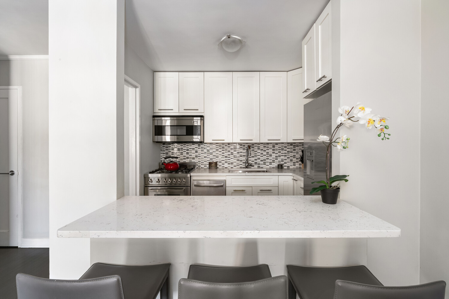 200 West 79th Street, Unit 12P Manhattan, NY 10024 - Photo 4 of 10 a kitchen with stainless steel appliances a white table and chairs in it