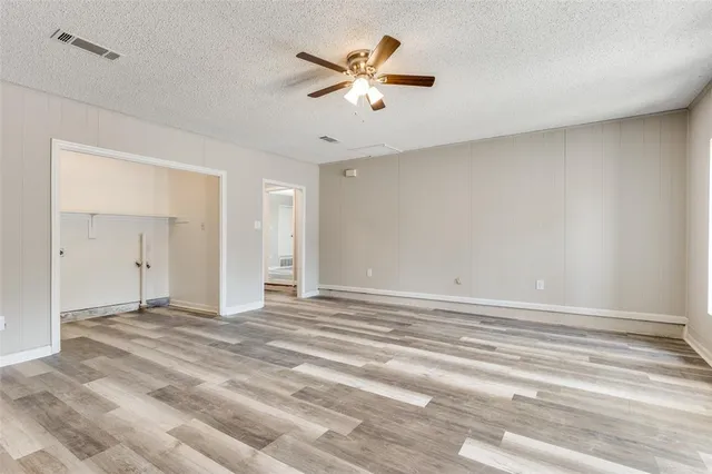 a view of an empty room with cabinet and a ceiling fan