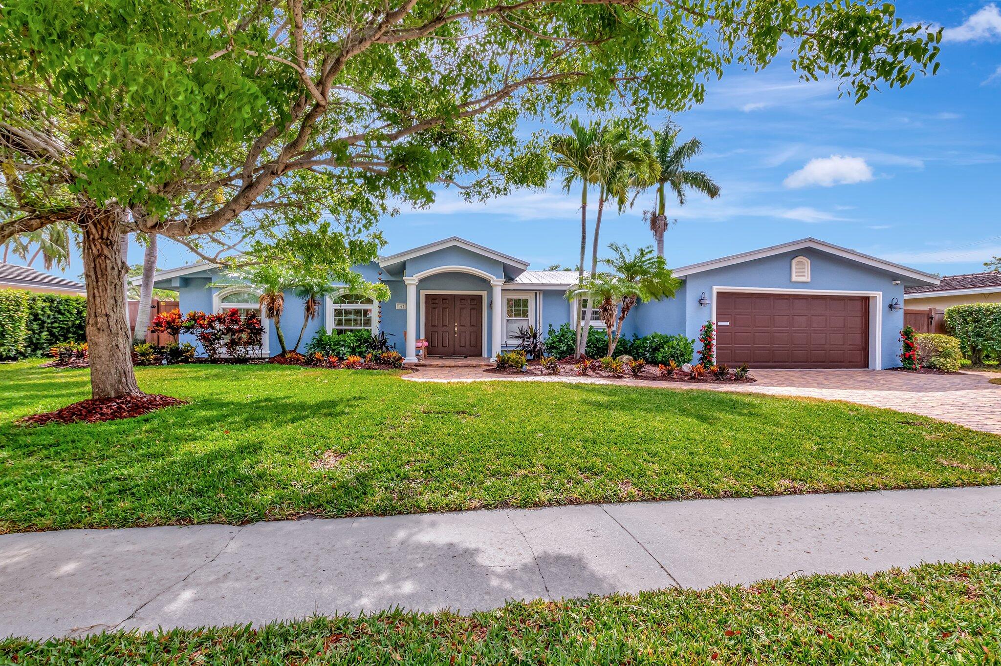 166 Southwest 8th Avenue Boca Raton, FL 33486 - Photo 1 of 25 a front view of a house with a garden and trees