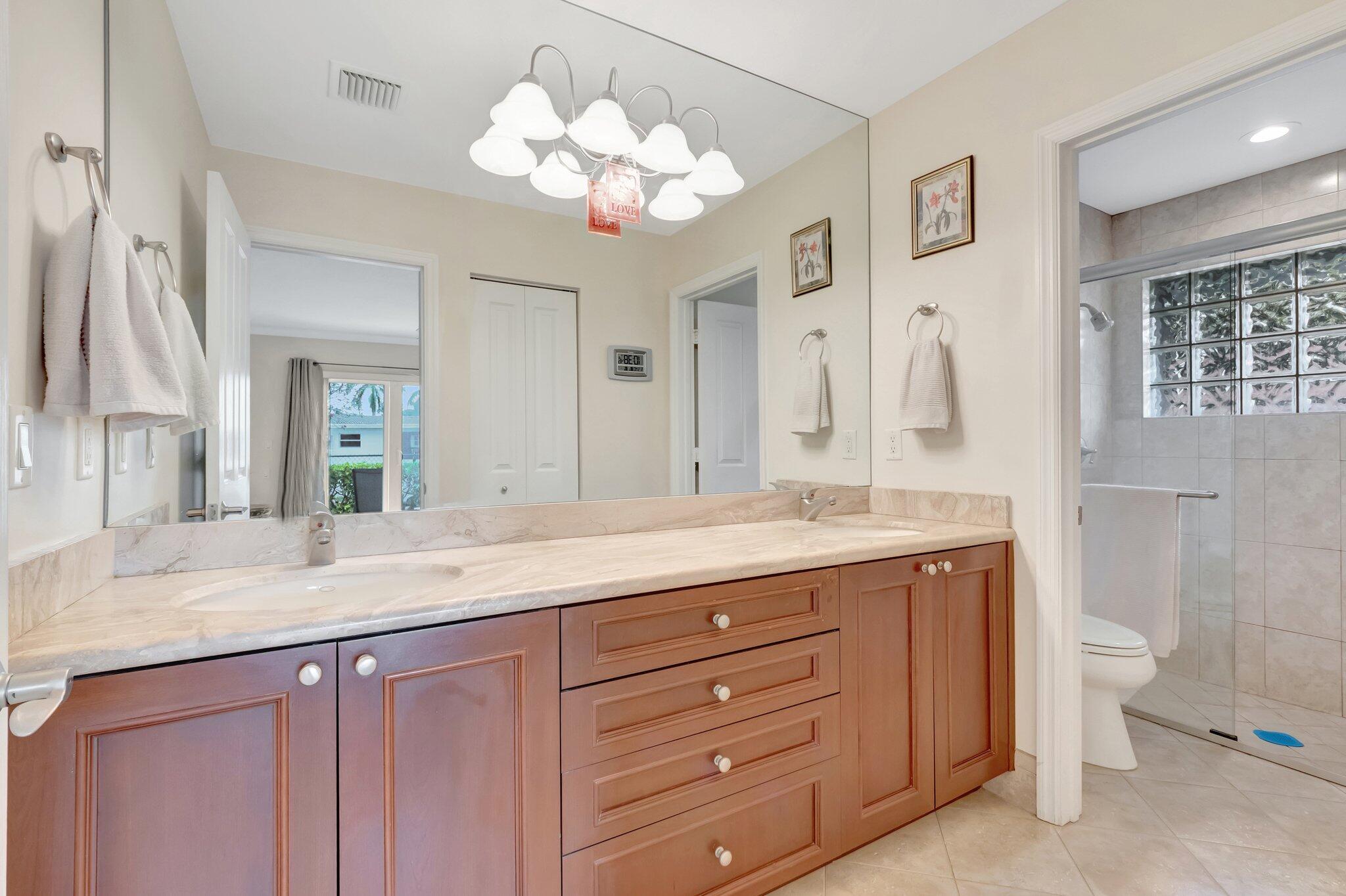 166 Southwest 8th Avenue Boca Raton, FL 33486 - Photo 11 of 25 a bathroom with a granite countertop double vanity sink a mirror and a shower