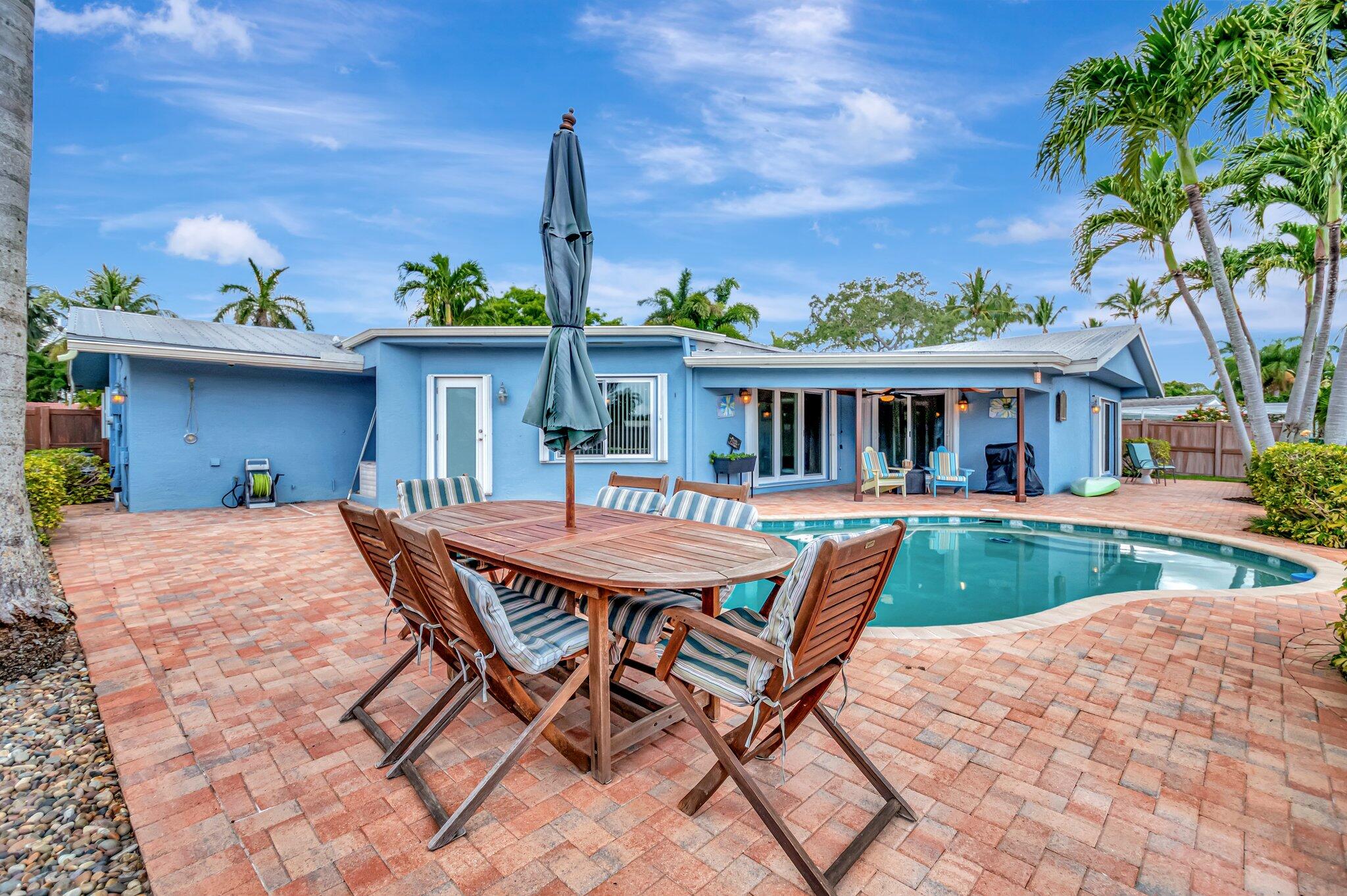 166 Southwest 8th Avenue Boca Raton, FL 33486 - Photo 25 of 25 a view of a house with a yard and table and chairs under an umbrella