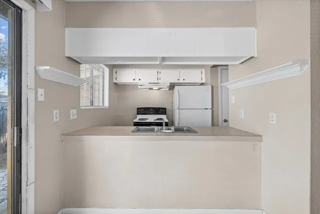 a kitchen with kitchen island a sink a stove and white cabinets