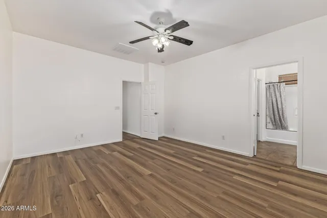 an empty room with wooden floor and ceiling fan