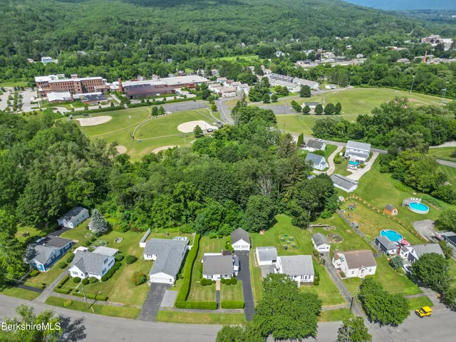 an aerial view of residential houses with outdoor space and trees all around
