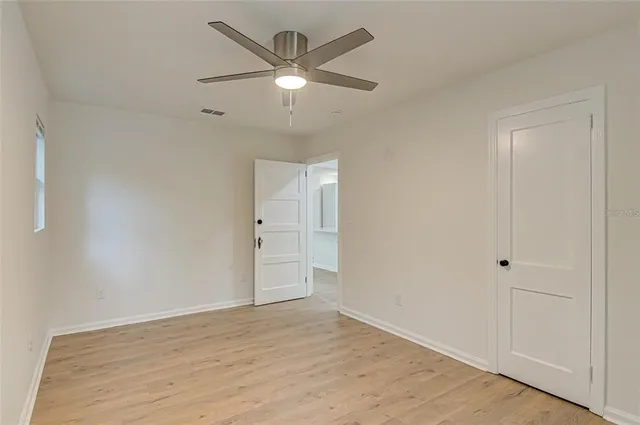 an empty room with wooden floor and ceiling fan