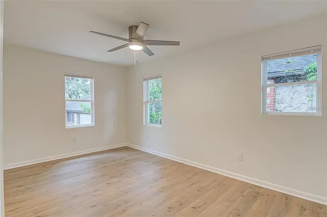 a view of an empty room with wooden floor and a window