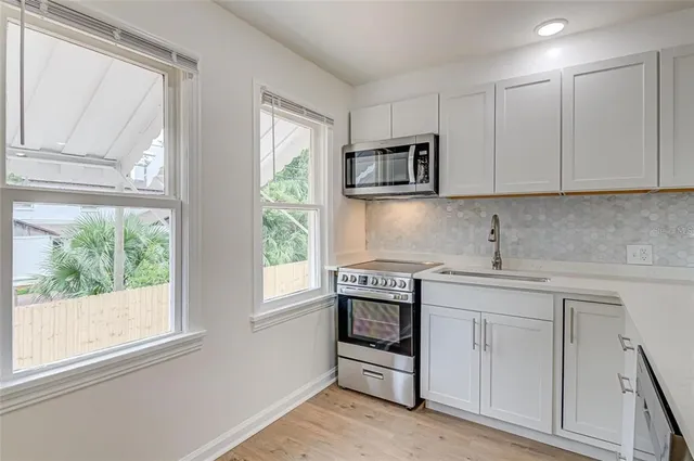 a kitchen with white cabinets and a window