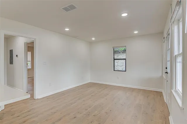 an empty room with wooden floor and windows