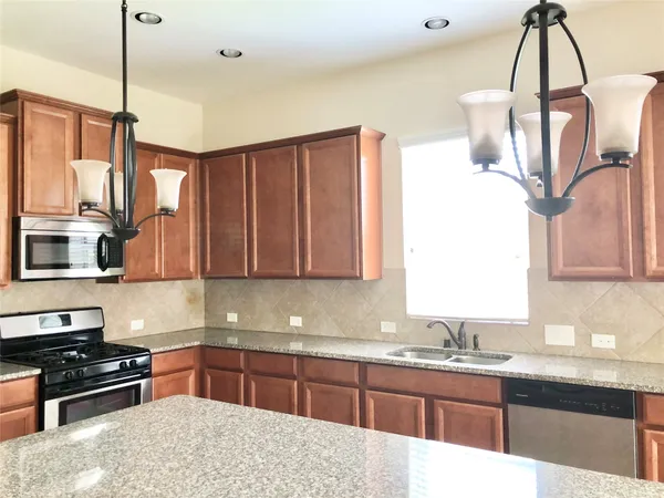 a kitchen with stainless steel appliances granite countertop a stove a sink and a microwave
