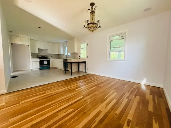a view of a room with kitchen island stainless steel appliances wooden floor and living room view