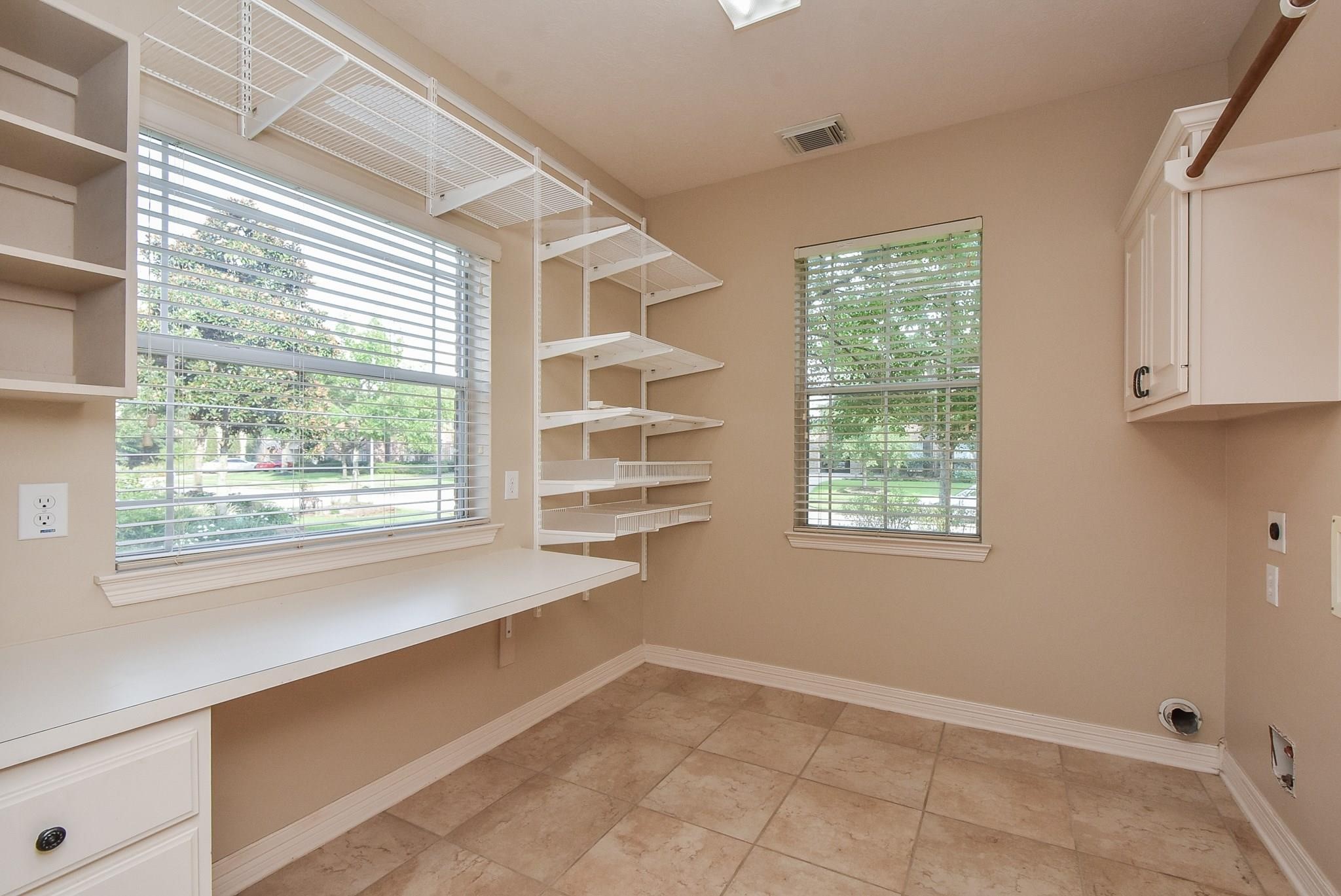 9722 Blue Cruls Way Spring, TX 77379 - Photo 23 of 49 Bright laundry toom off the kitchen with folding counter, cabinet storage and clothes chute.
