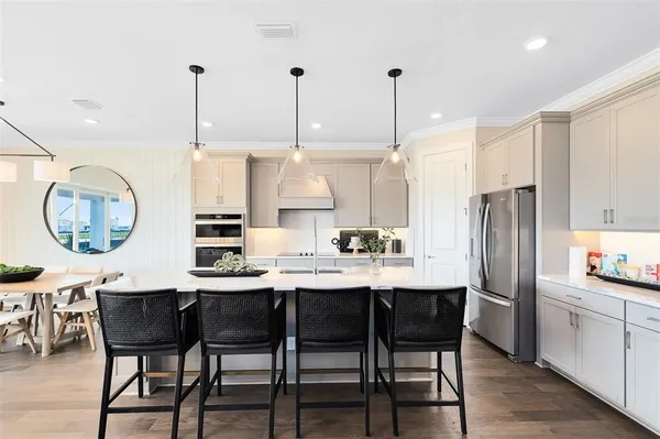 a kitchen with stainless steel appliances kitchen island granite countertop a table chairs and a refrigerator