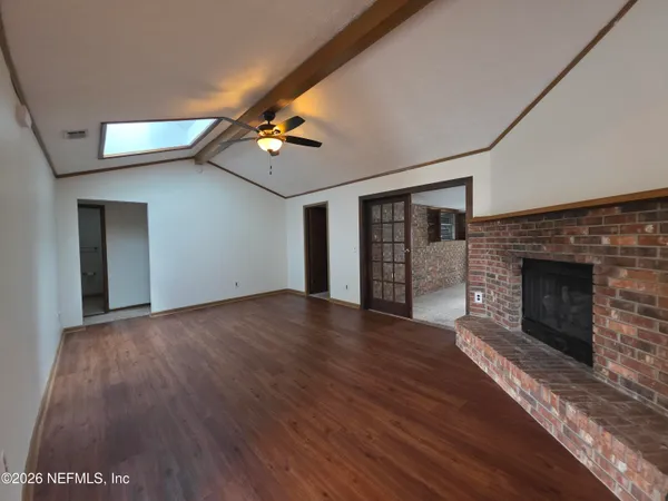 a view of empty room with wooden floor and fireplace