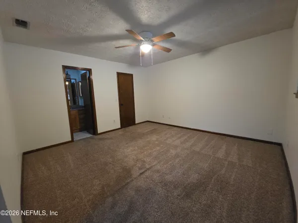 an empty room with closet and ceiling fan